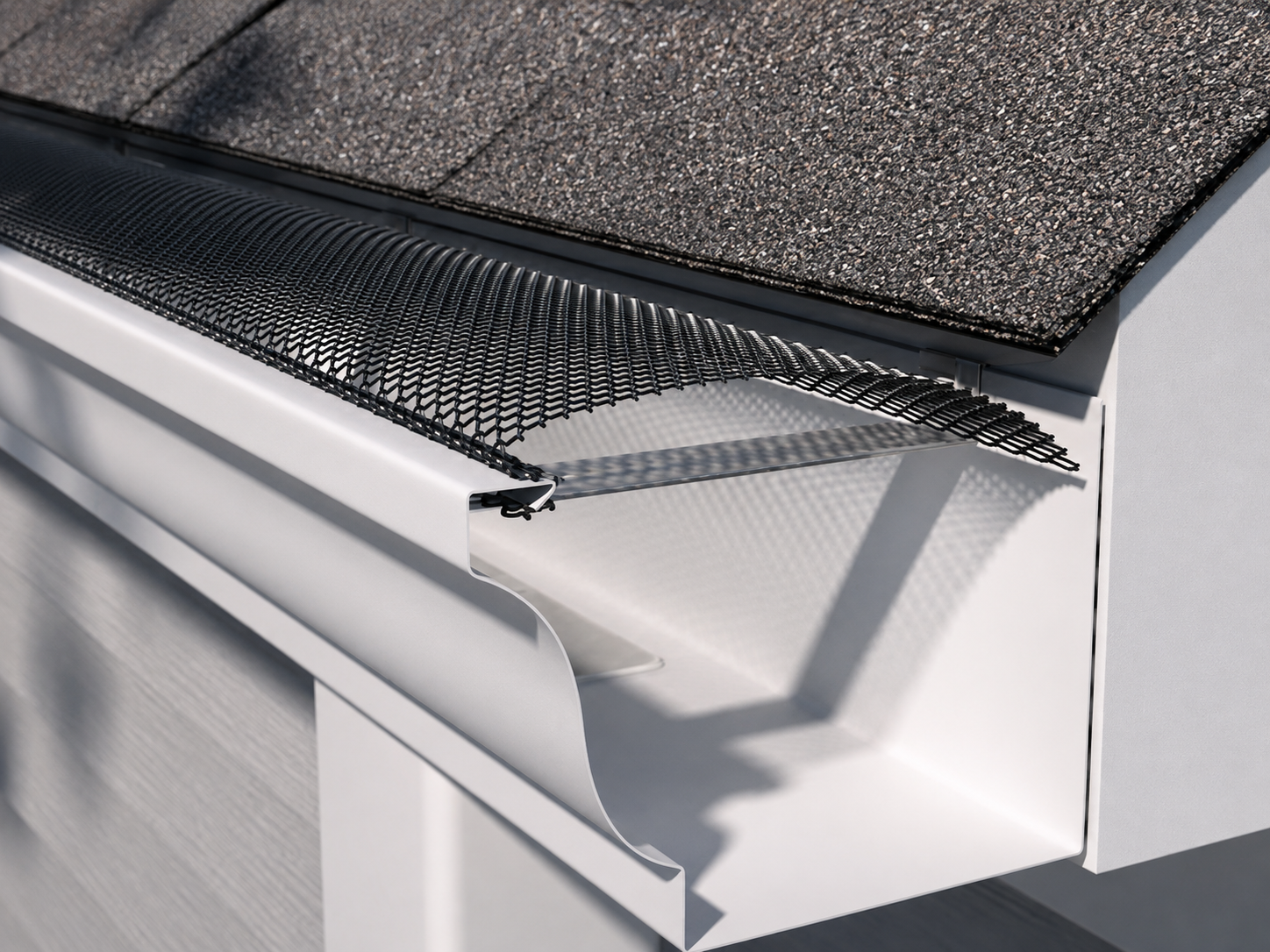 Mesh leaf guard installed over a white seamless gutter along a shingle roof edge